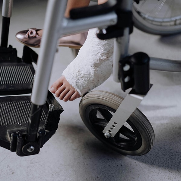 Photo d'un pied plâtré en gros plan sur un fauteuil roulant, le fonds de garantie est là pour aider.